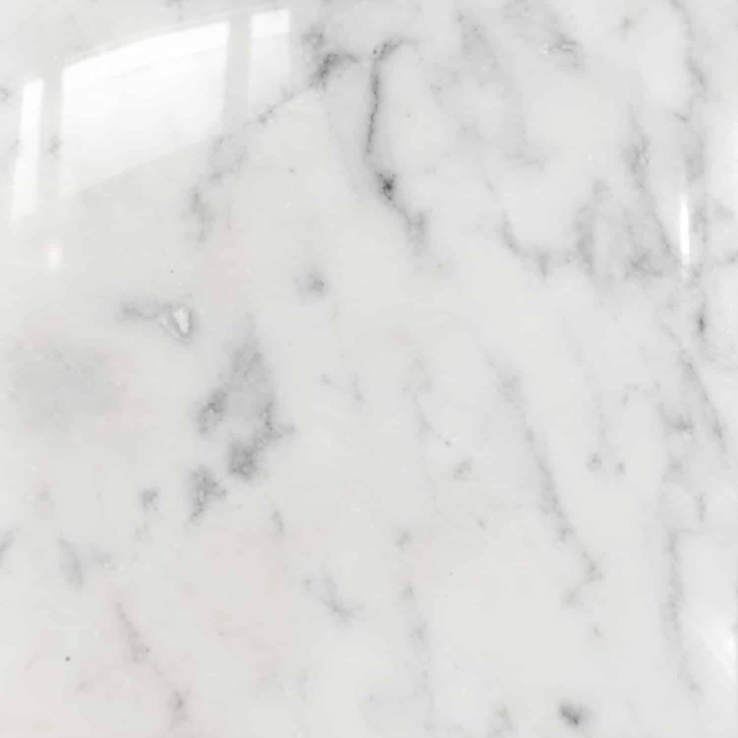 Marmor Bianco Carrara mit weißer Grundfarbe und feiner grauer Maserung, hochglanzpolierte Oberfläche in Detailansicht.
